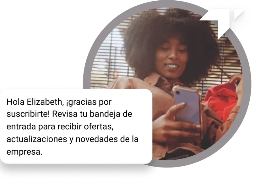 Chica de cabello rizado sentada en el piso mirando su teléfono en busca de un mensaje de agradecimiento recibido por su suscripción