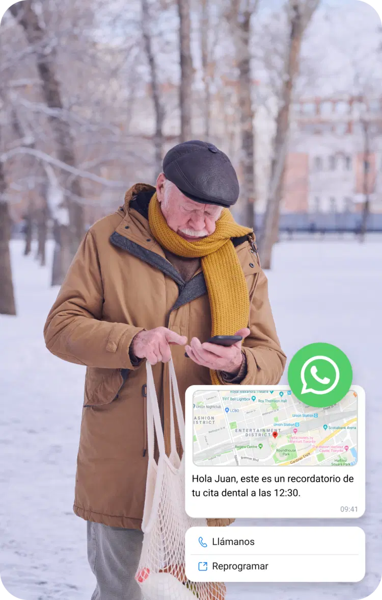 Anciano en la nieve comprobando la ubicación de su móvil a través de un mensaje empresarial de WhatsApp